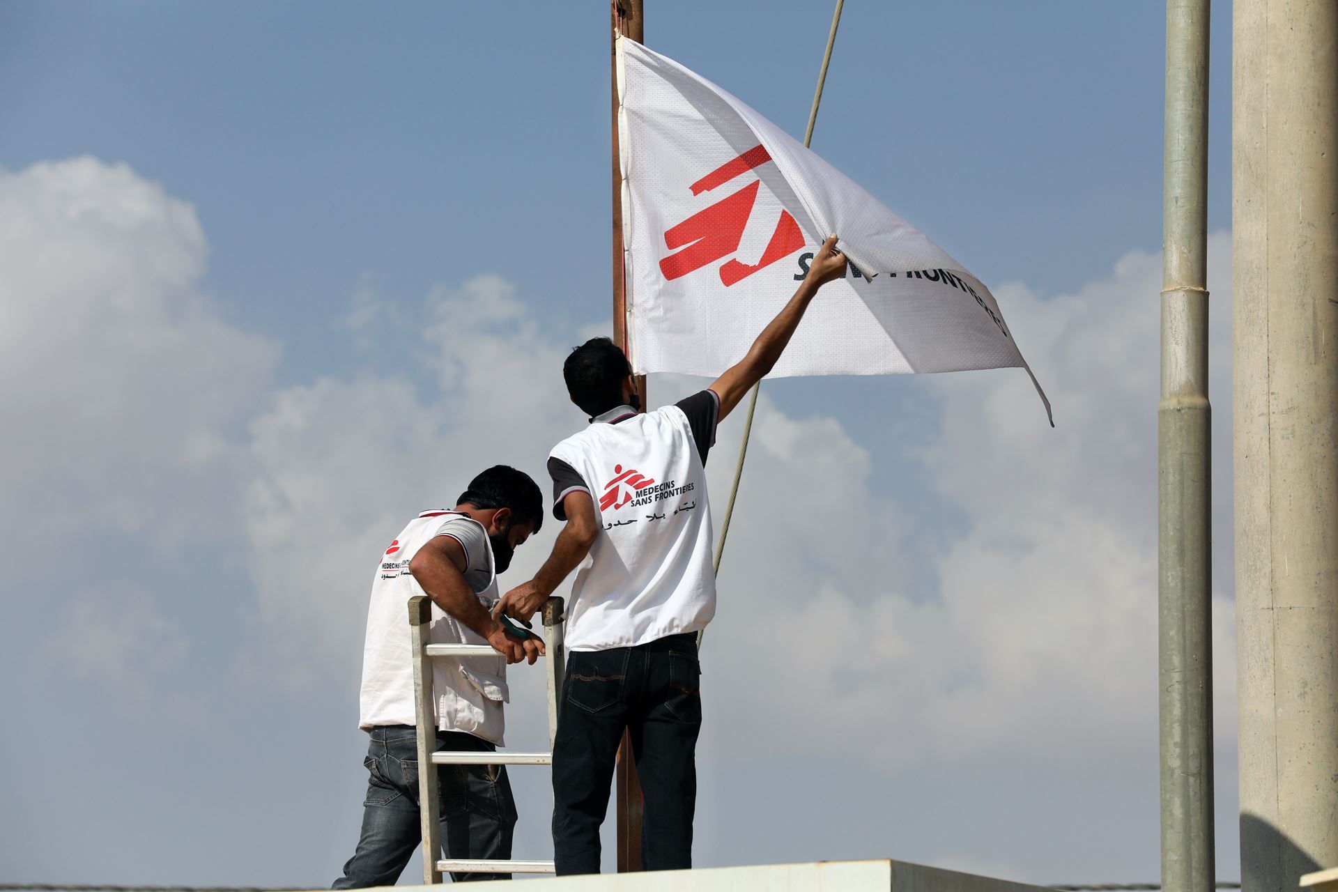 Two MSF staff raising MSF flag